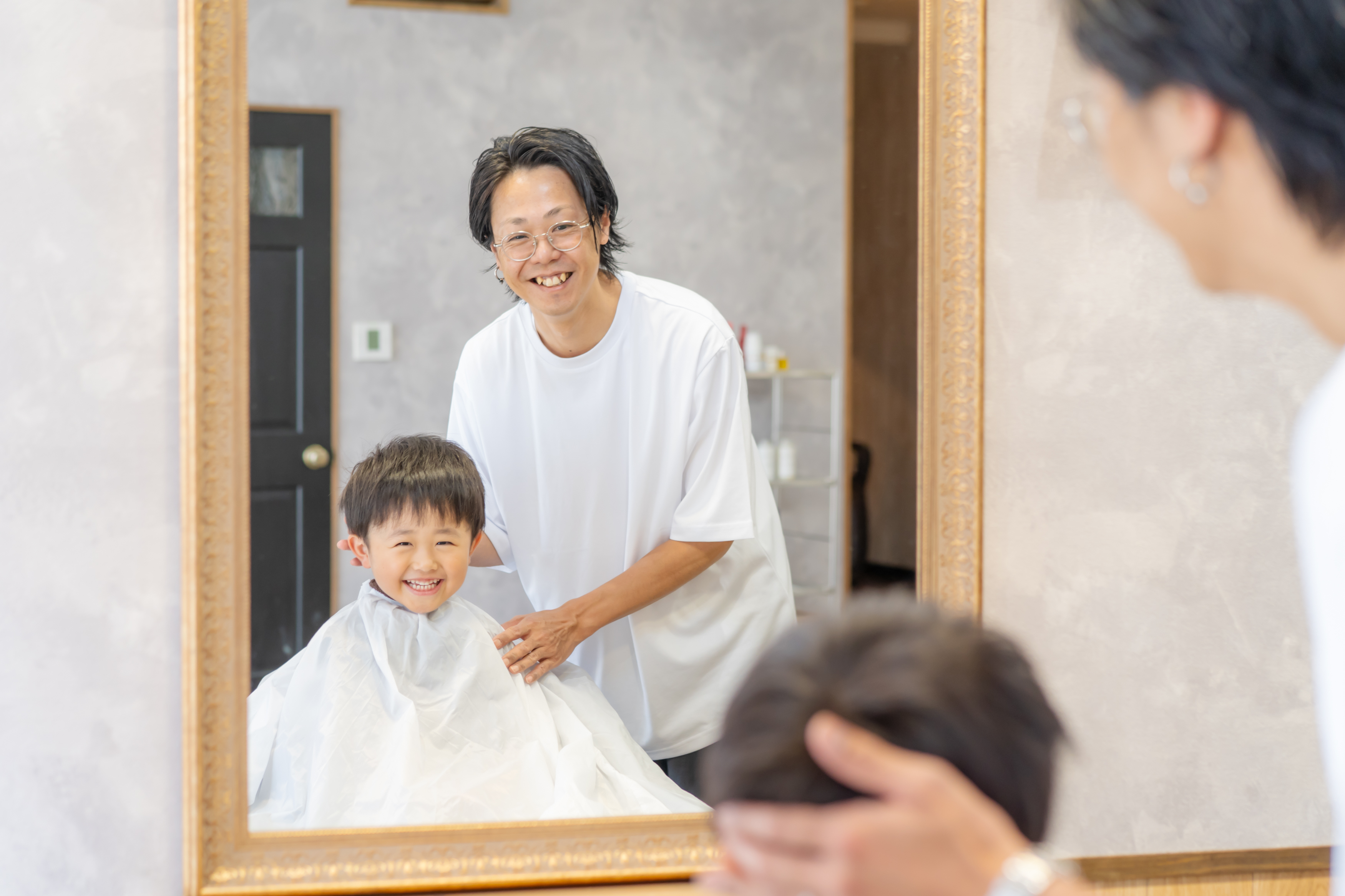 仕上がった艶髪を鏡で確認しながらスタイリストと相談する女性、落ち着いた個室サロンの空気感